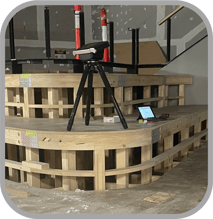 Customer Image - Flexijet in center shot on a construction site, shows Flexijet with IPad on job site, taking measurement of space for staircase. 