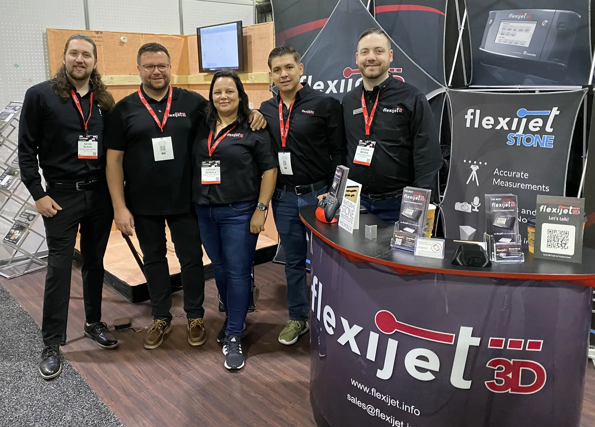 Photo of Flexijet Measurement Expert Team, stood in a group, smiling happy team - Kevin, Daniel, Leticia, Josa, Steven exhibiting at an event on Flexijet trade show stand.